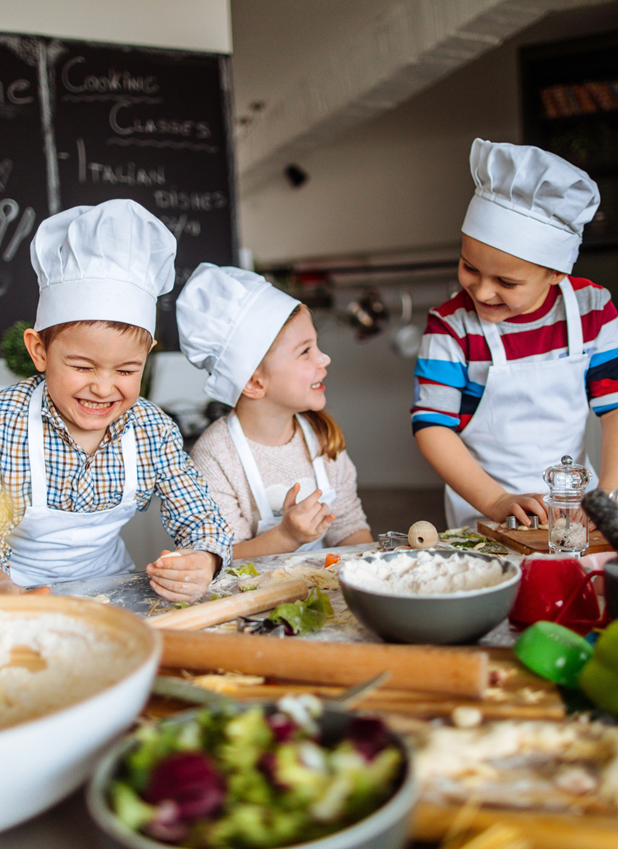 2 boys and 1 girl laugh as they bake dressed as chefs
