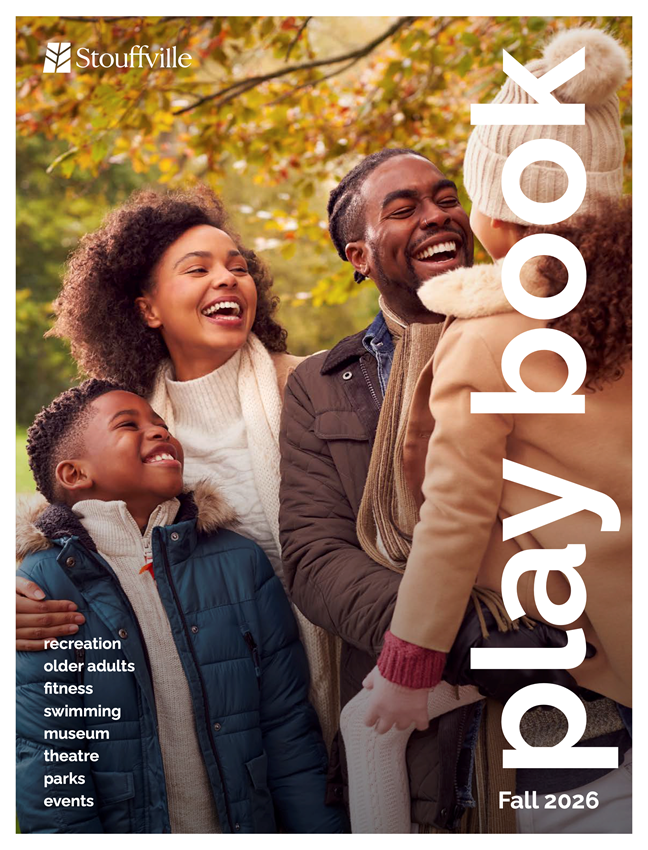 A family of four smiling outdoors near trees